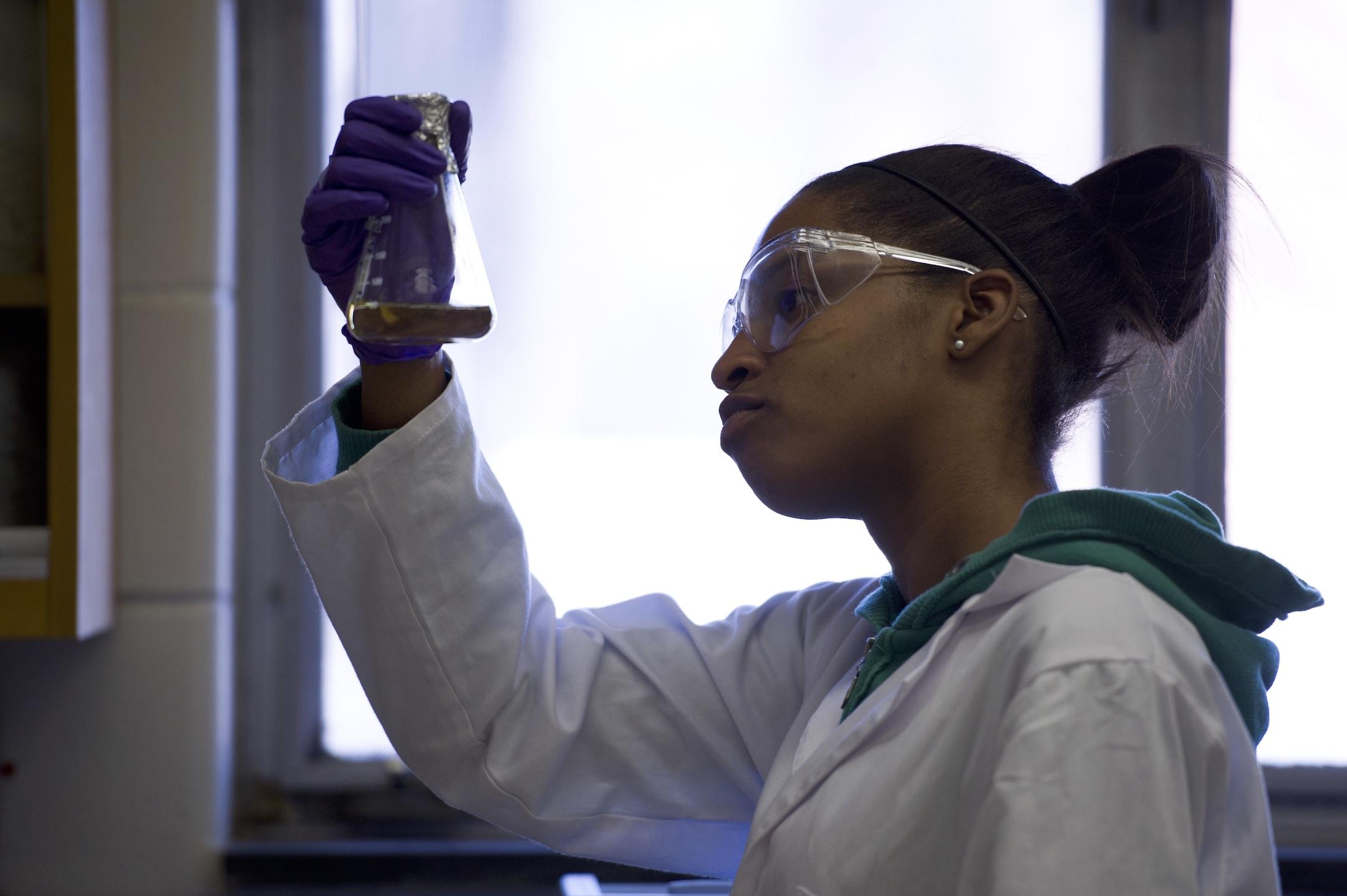 student in lab with beaker